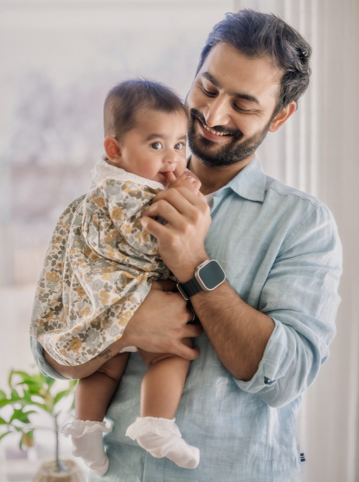 Arya in her dad's arms by the window, holding his finger
